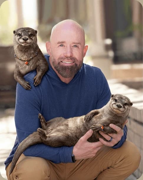 Dr. Bruce Rumsey holding two otters